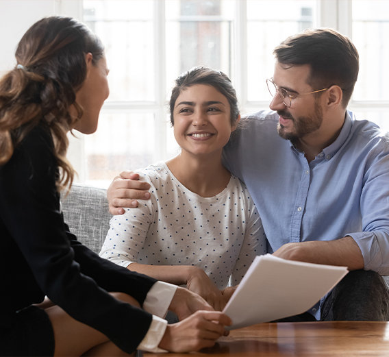 Man putting his arm around woman in mortgage pre-approval meeting with mortgage broker.